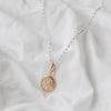 A 9ct gold moon-shaped pendant necklace laid out on a white fabric surface.