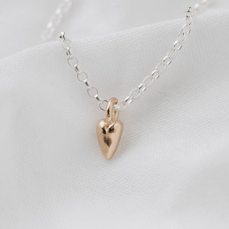 A small 9ct gold heart pendant attached to a sterling silver belcher chain necklace, displayed on a white background.