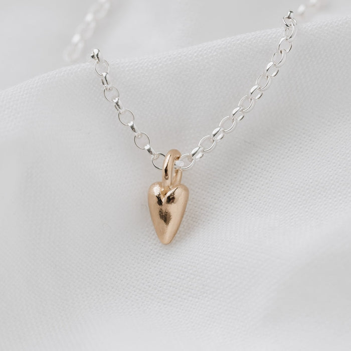 A small 9ct gold heart pendant attached to a sterling silver belcher chain necklace, displayed on a white background.