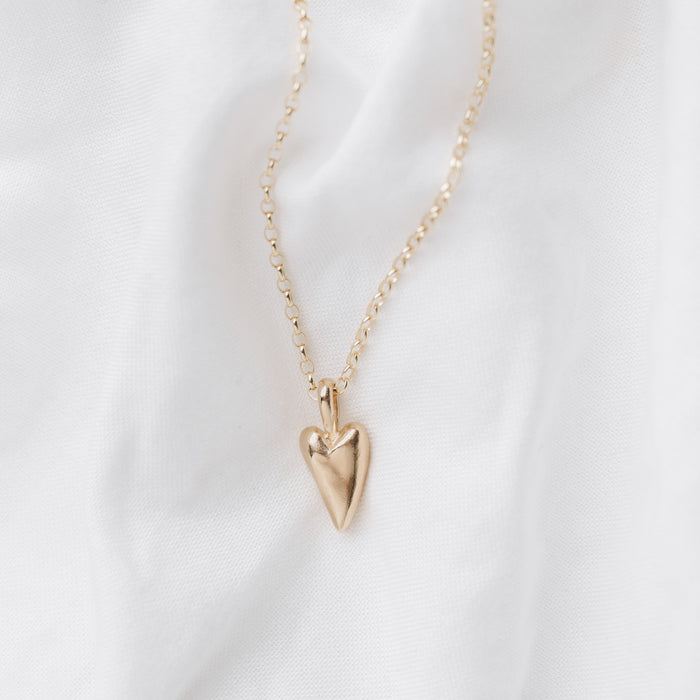 A 9ct gold heart-shaped pendant necklace laid out on a white surface.