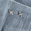 Two silver bee-shaped earrings on a denim background