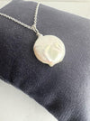 Coin pearl on a silver chain on a navy cushion