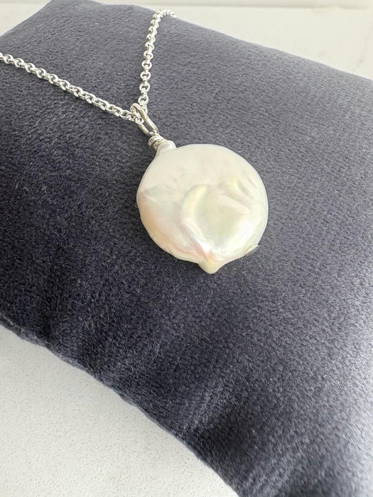 Coin pearl on a silver chain on a navy cushion