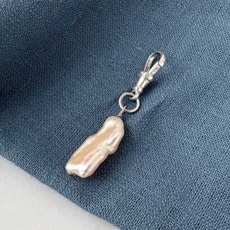 Pearl charm with a clasp on a blue fabric background