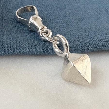 Silver pendant with geometric design on a blue cushion background