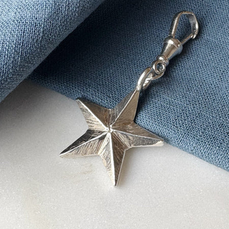 Silver star-shaped pendant on a blue fabric background
