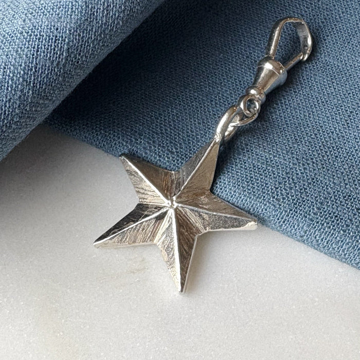 Silver star-shaped pendant on a blue fabric background