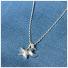 A silver pendant featuring a crescent moon and a small guiding star, hanging from a silver chain on a blue textured background.