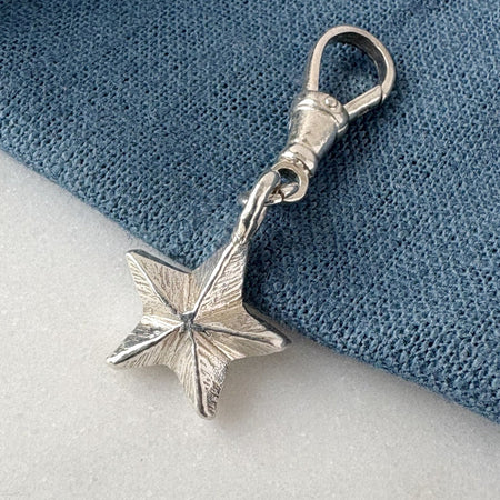 Silver star-shaped charm on a blue and white fabric background
