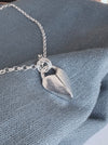 Silver heart-shaped pendant necklace on a soft navy background
