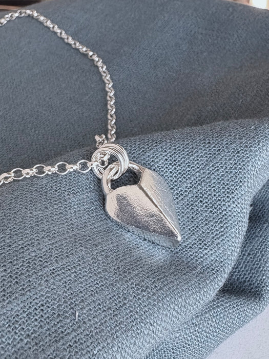 Silver heart-shaped pendant necklace on a soft navy background