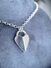 Silver heart-shaped pendant necklace on a soft grey background