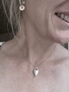 Silver heart-shaped pendant necklace on a soft grey background