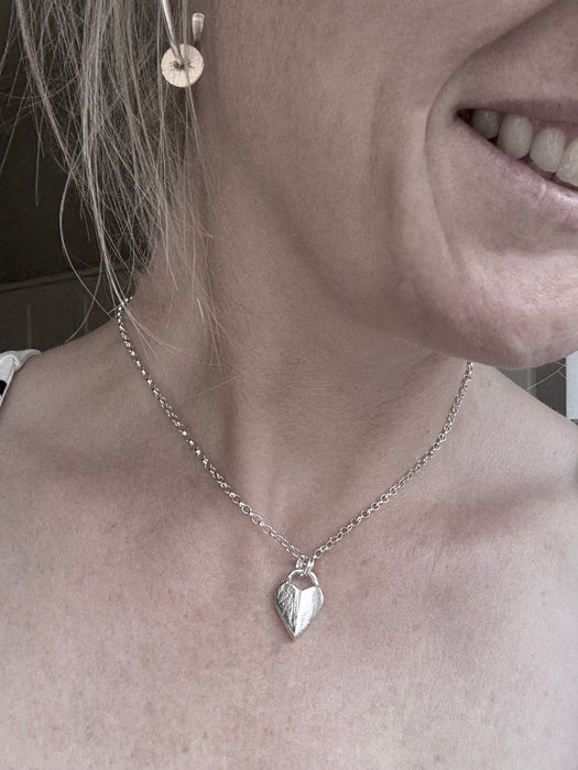 Silver heart-shaped pendant necklace on a soft grey background