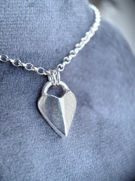 Silver heart-shaped pendant necklace on a soft grey background