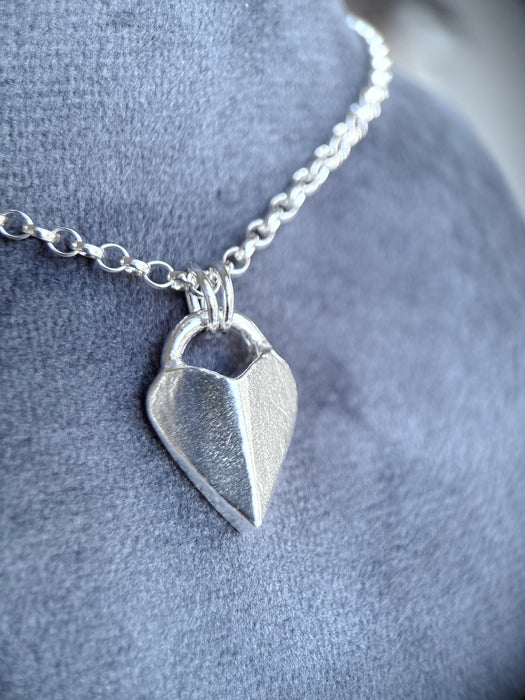 Silver heart-shaped pendant necklace on a soft grey background