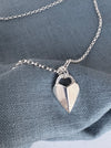 Silver necklace with a heart-shaped pendant on a blue fabric background