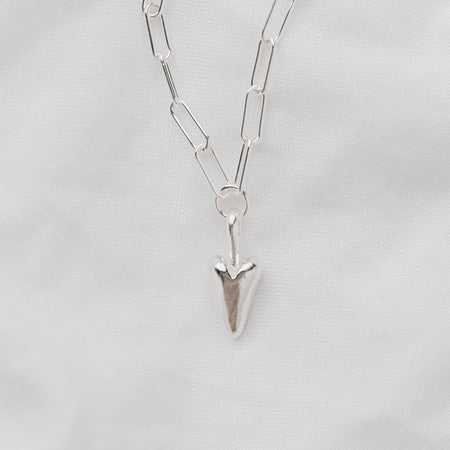 A chunky silver heart hanging from a silver trace chain necklace