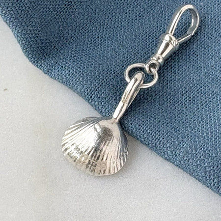 Silver shell charm on a blue and white background