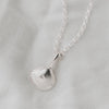 Silver shell pendant necklace on a light gray background