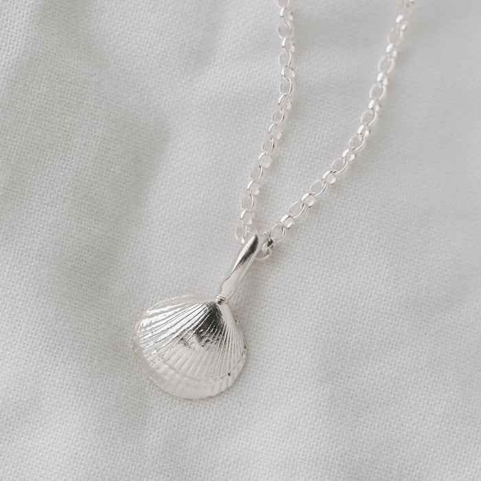 Silver shell pendant necklace on a light gray background