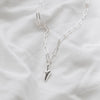 A chunky silver heart hanging from a silver trace chain necklace