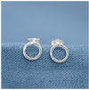 Mini halo or circle stud earrings on a light blue linen background