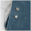 Miniature star stud earrings on a blue linen background