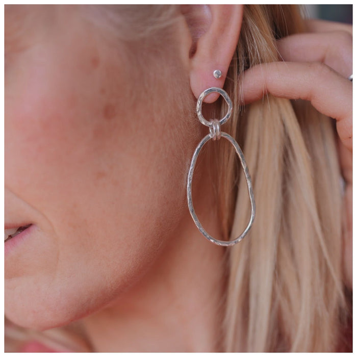Organically shaped double hooped dangly earrings on a blonde female with a single silver stud