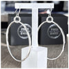 A pair of sterling silver hoop earrings with a hammered effect, displayed on a clear t bar earring holder