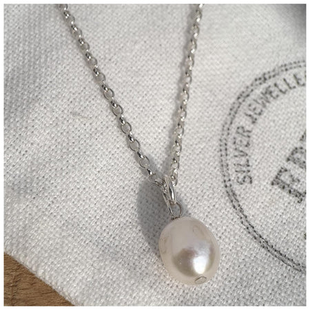 Small Freshwater pearl hanging from a silver chain on a white linen bag
