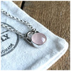 A round rose quartz pendant set in a sterling silver mount, with a chunky silver belcher chain.