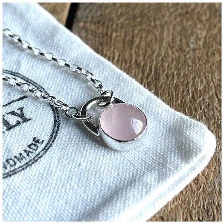 A round rose quartz pendant set in a sterling silver mount, with a chunky silver belcher chain.
