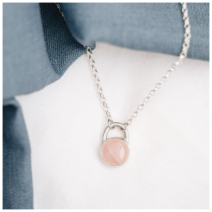 A round rose quartz pendant set in a sterling silver mount, with a chunky silver belcher chain.