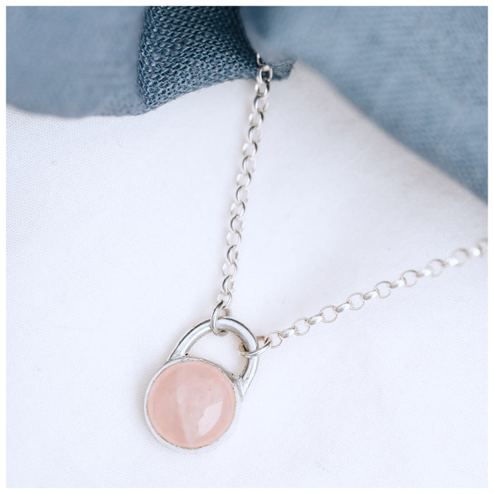A round rose quartz pendant set in a sterling silver mount, with a chunky silver belcher chain.