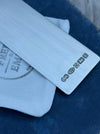 A close-up of a silver metal bookmark with a large hallmark, resting on a white textured cloth over a dark blue fabric background.