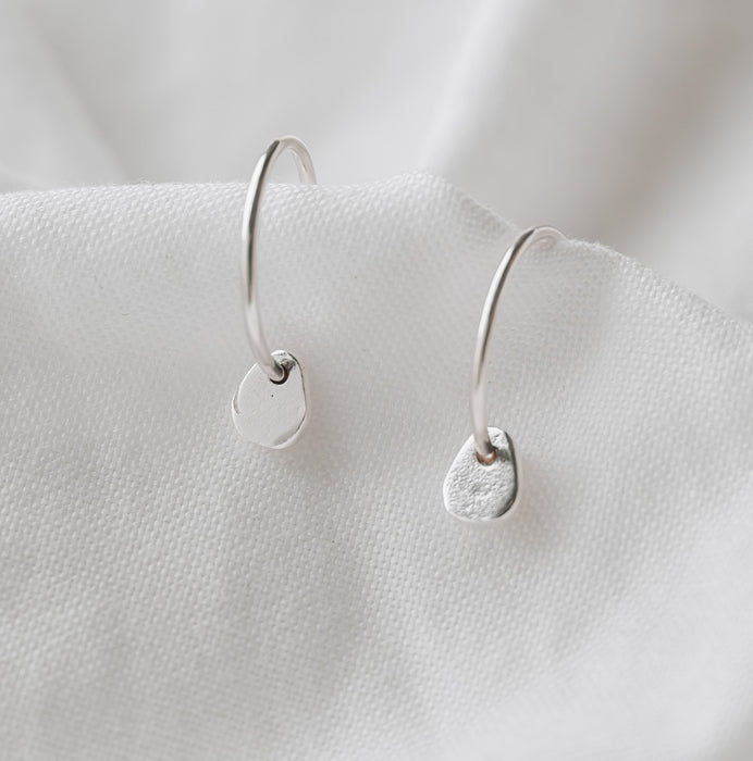 silver hoops with a small pebble on a white linen background