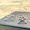 Silver 'X' shaped earrings on a grey textured surface, kiss earrings