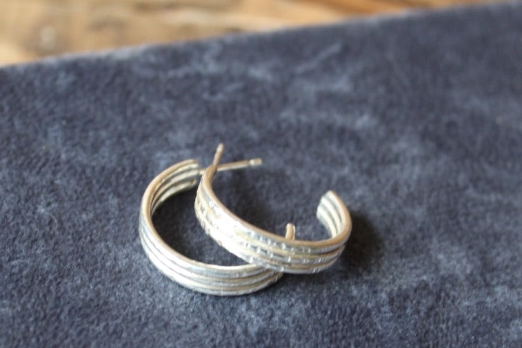 Silver hoop earrings on a dark fabric background