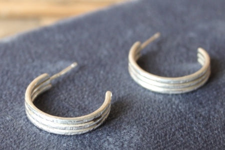 Pair of silver hoop earrings on a dark fabric background