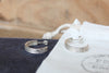 Silver hoop earrings on a F&E branded jewellery pouch with a blurred wooden surface in the background.