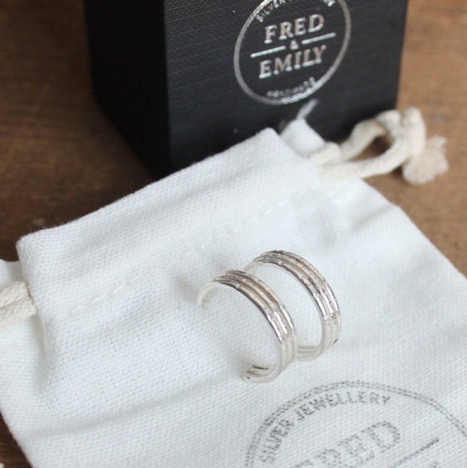 Silver hooped earrings on a white cloth with 'FRED & EMILY' branding in the background.