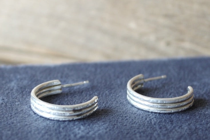 Pair of silver hoop earrings on a textured surface