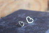 two small silver heart earrings studs sat on a blue background