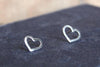 two small silver heart earrings studs sat on a blue background