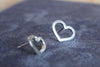 two small silver heart earrings studs sat on a blue background