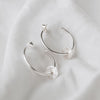 Sterling silver hoops with a textured disc on each, laying on a white linen background with butterfly backs