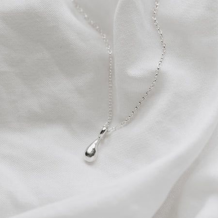a delicate silver droplet hanging on a belcher chain