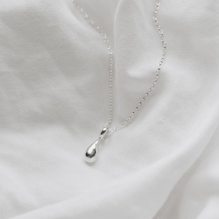 a delicate silver droplet hanging on a belcher chain