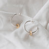 Silver hoops with a gold filled disc, textured to create a sparkle sitting on a white linen background